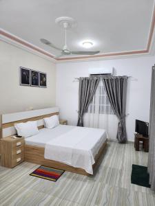 a bedroom with a large white bed and a television at Résidence Osiris in Cotonou