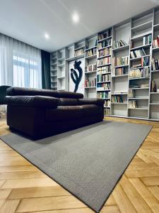 a black leather couch in a living room with bookshelves at Alexander library apartment in Košice