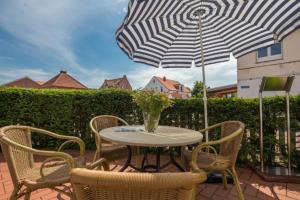 a table with chairs and an umbrella on a patio at Haus Anna-Margarete in Norderney