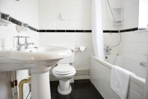 a white bathroom with a sink and a toilet and a tub at The Riviera Hotel & Apartments - Alum Chine in Bournemouth
