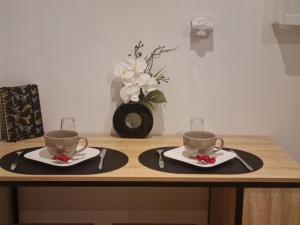 a table with two coffee cups and a vase with flowers at SPA Rome Antique in Courrières