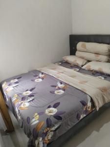 a bed with a purple blanket with flowers on it at Vila Alief Batu in Tlekung
