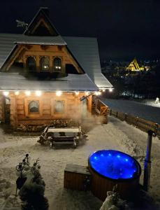 ザコパネにあるGóralska Chatka 3 Highland Cottage - Jacuzzi, Sauna, Split AC, Private parking, Mountains Viewの夜の雪の中にある浴槽のある家
