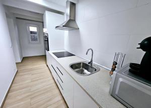 a small white kitchen with a sink and a microwave at Casa Los Volcanes a primera línea del mar in Teguise +19 photos