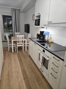 a kitchen with white cabinets and a table with chairs at Studio Apartment Aurora in Rovaniemi +1 photo
