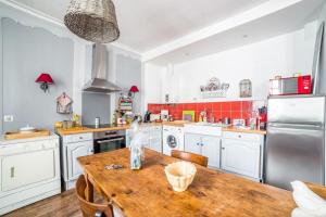 une cuisine avec des placards blancs et une table en bois dans l'établissement Appartement de charme coeur historique parking privé, à Vannes