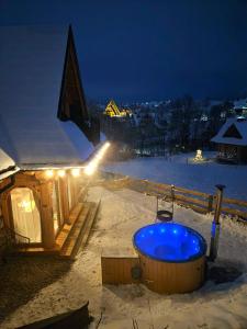 a hot tub in the snow at night at Góralska Chatka 2 Highland Cottage - Split AC, Jacuzzi, Sauna, Private parking, Mountains View, Garden, Zakopane in Zakopane