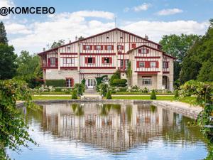 ein großes Haus mit einem Teich davor in der Unterkunft Appartement 2 pers. RDC à Cambo-les-Bains avec Internet et Animaux admis - FR-1-495-62 in Cambo-les-Bains