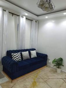 a blue couch in a living room with curtains at Traven Homes - 1BR Unit in Nairobi