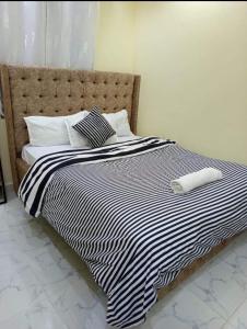 a bed with a black and white blanket and pillows at Traven Homes - 1BR Unit in Nairobi