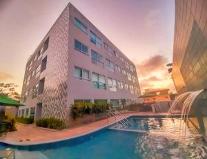 a building with a swimming pool in front of a building at Porto Sunset Flat Aline Duque in Porto De Galinhas