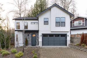 a white house with a blue garage door at Elegant 3-Story House with Private Backyard in WA in Kirkland