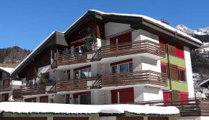 a building with snow on the ground in front of it at Apartment Birkenstrasse 54 Engelberg in Engelberg