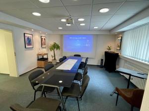 a conference room with a table and chairs and a screen at Smart In Göttingen - Apartments & Rooms in Göttingen