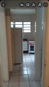 a kitchen with a refrigerator and a tile floor at Apartamento na praia grande in Praia Grande