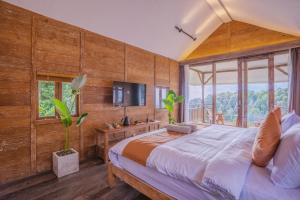 a bedroom with a large bed and a tv at Ocean & Mountain View Villa, Waterfalls, Munduk Eco-Luxe by Santrian in Munduk