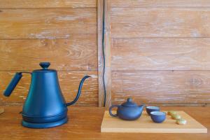 a blue tea kettle and three cups on a wooden table at Ocean & Mountain View Villa, Waterfalls, Munduk Eco-Luxe by Santrian in Munduk