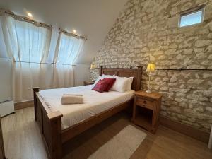 a bedroom with a bed and a stone wall at La Grange D'EsusTerra - Piscine - 6 pers - Rêve au Mans in Aubigné-Racan +18 photos