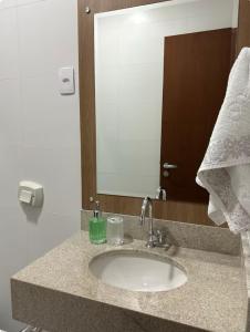 Un mostrador de baño con un lavabo y un espejo. en Apartamento aconchegante próximo ao mar em Itapoá, en Itapoa