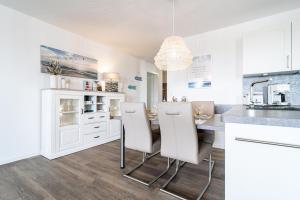 a kitchen with white cabinets and a table and chairs at Seaside 49 3 N in Wangerland +24 photos