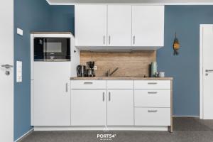 a kitchen with white cabinets and a blue wall at Ferienwohnung Bude 12 Dagebüll in Dagebüll