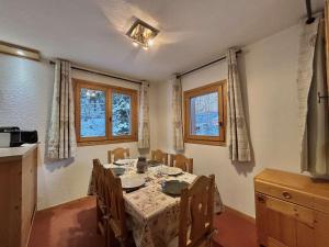 a dining room with a table and chairs and two windows at Appartement pour 6, centre Méribel, proche commerces et pistes, piscine l'été - FR-1-180-303 in Méribel