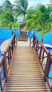 a wooden bridge over a body of water with palm trees at MAUÍ BEACH Tamandaré Flat Terreo in Tamandaré