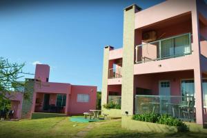 ein rosafarbenes Gebäude mit einem Picknicktisch davor in der Unterkunft Complejo Las Liebres in San Lorenzo