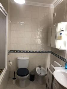 a white bathroom with a toilet and a sink at Casa das Conchas in Ericeira