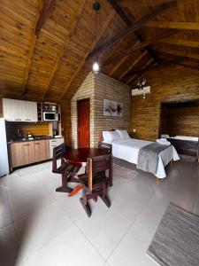 a bedroom with a bed and a table and a kitchen at Vila Vicença Natural Refuge in Praia Grande