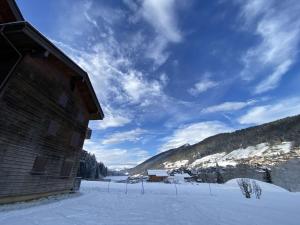 a building in the snow next to a mountain at Studio cosy avec jardinet, près des pistes et centre, 4/5 pers, Le Grand-Bornand - FR-1-458-184 in Le Grand-Bornand