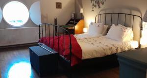 a bedroom with a bed with a red blanket and two windows at B&B Bij Greet in Sellingen