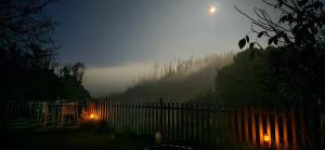 uma noite de nevoeiro com uma cerca no quintal em RR Forest View em Ooty