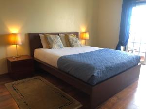 a bedroom with a large bed with two lamps at Casa das Conchas in Ericeira