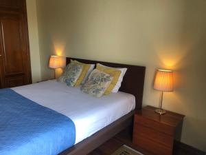 a bedroom with a bed with two lamps on it at Casa das Conchas in Ericeira