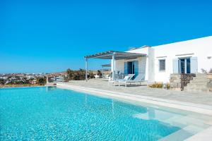 a swimming pool in front of a white house at Villa Levantes - quiet location with private pool in Márpissa