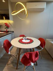 a white table with red chairs and a plate on it at Duplex cobertura Centro Gramado in Gramado