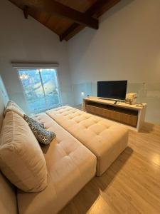 a living room with a large couch and a television at Duplex cobertura Centro Gramado in Gramado
