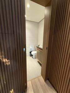 a bathroom with a toilet and a sink and a door at Duplex cobertura Centro Gramado in Gramado