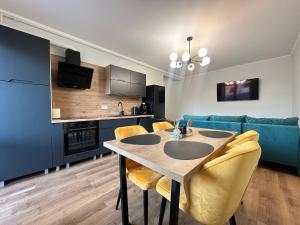 a kitchen and dining room with a table and yellow chairs at Nova Apartment in Şelimbăr
