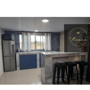 a kitchen with a counter with stools and a refrigerator at Utopía Hogar in Balneario Argentino +19 photos
