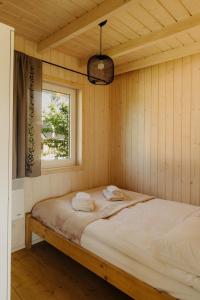 Bett in einem Holzzimmer mit Fenster in der Unterkunft Osada Chmiel in Chmielno