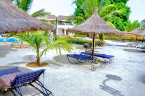eine Gruppe von Stühlen und Sonnenschirmen an einem Strand in der Unterkunft La Villa Moringa, meublée et équipée in Saly Portudal