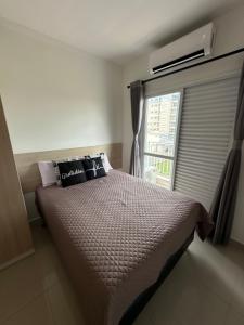 a bedroom with a large bed and a window at Apartamento Primavera Boituva COM AR CONDICIONADO! in Boituva
