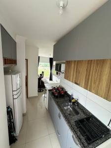 a kitchen with a sink and a refrigerator at Apartamento Primavera Boituva COM AR CONDICIONADO! in Boituva