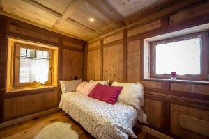 una camera con un letto in una camera in legno con due finestre di Historic Residenze Loo Bach a Gressoney-Saint-Jean