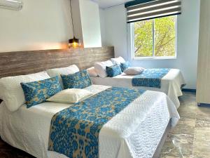 a hotel room with two beds and a window at Hotel Los Maderos in Cali