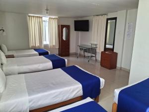 a hotel room with three beds and a table at Hotel Sideral AQP in Arequipa