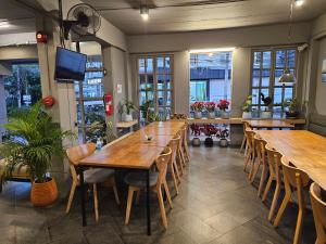 um restaurante com mesas e cadeiras de madeira e janelas em Mandalar Arch 39 Hotel em Chiang Mai