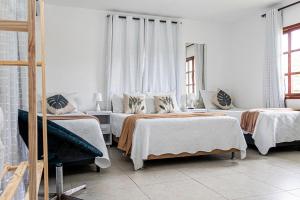 a bedroom with two beds and two windows at Tucanos Buzios in Búzios